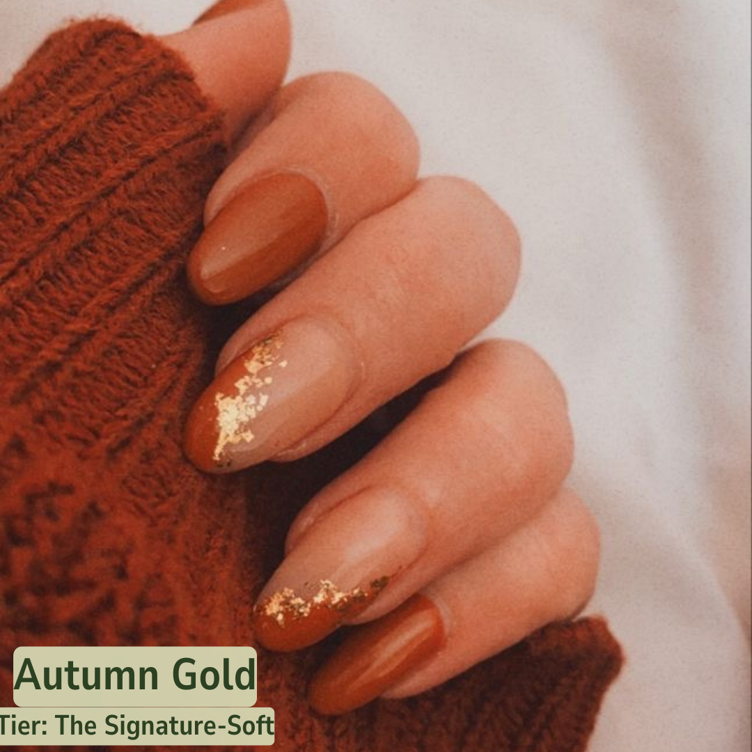 Hand with brown nail polish and gold glitter holding a textured brown object, with 'Autumn Gold' text overlay.