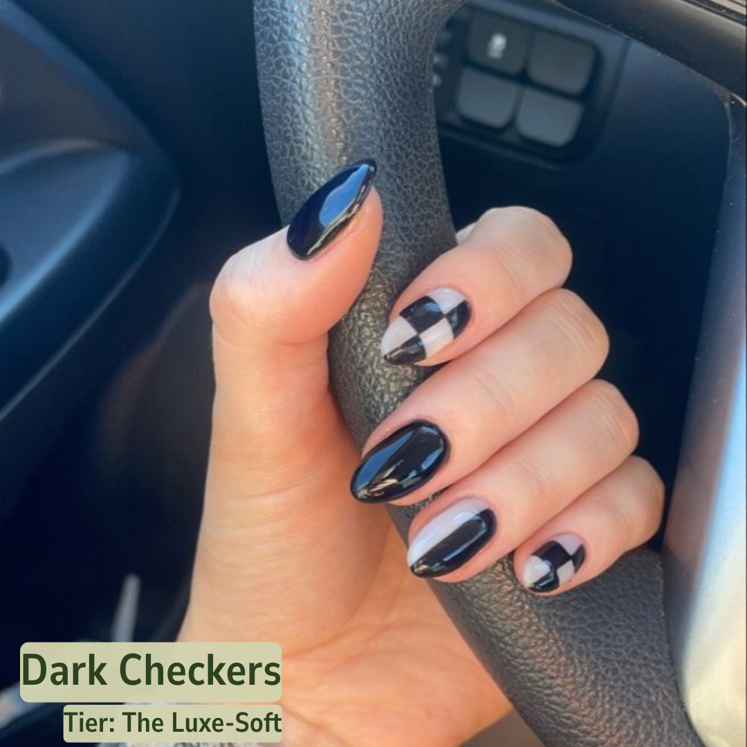 Hand with black and white checkered nail design holding a car steering wheel.